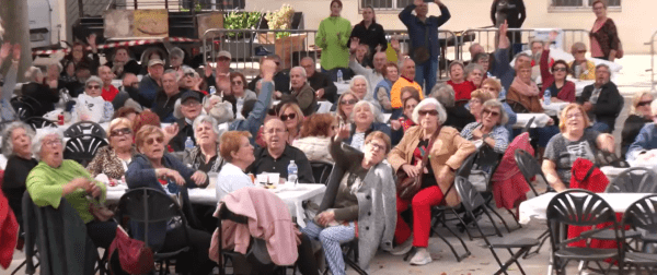 Grupo de personas sénior celebrando o animando en un evento al aire libre.