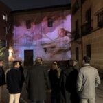 Groupe de personnes observant une projection d'art mural sur un bâtiment dans une rue de Madrid.
