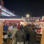 Marché de Noël nocturne sur la Plaza Mayor de Madrid, rempli de stands et de visiteurs.