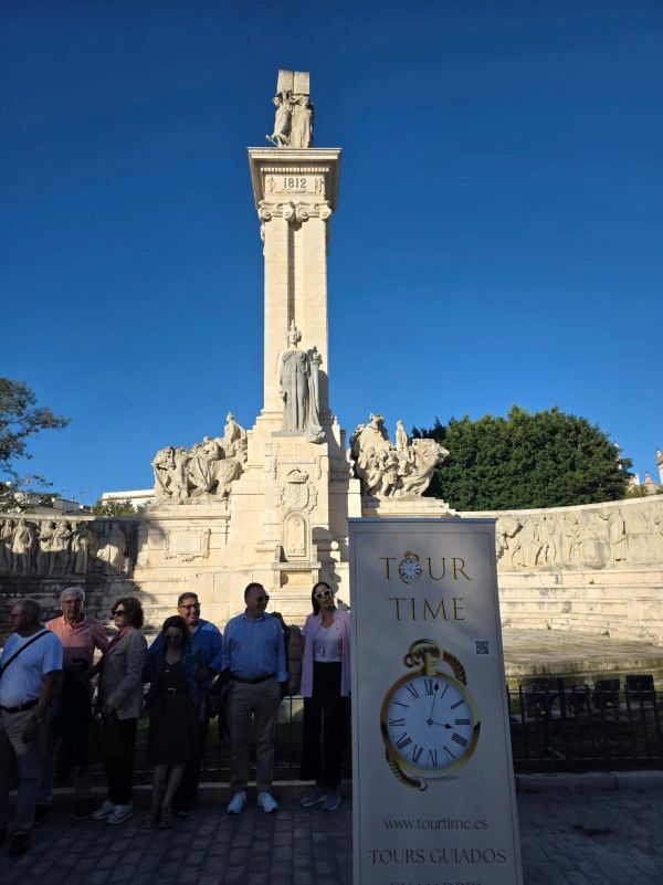 Grupo de turistas posando frente al Monumento a la Constitución de 1812 en la Plaza de España de Cádiz.