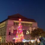 Le Théâtre Royal de Madrid illuminé avec un sapin de Noël géant et des gens sur la place.