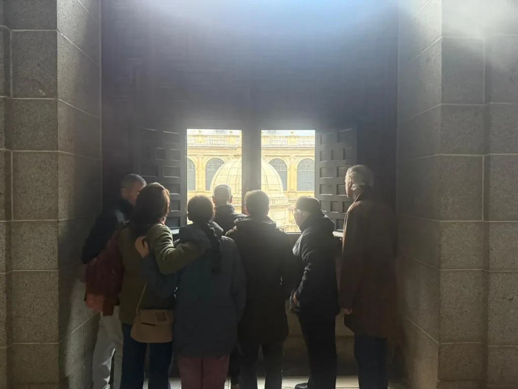 Grupo de visitantes en una visita guiada de Tour Time observando el Patio de los Evangelistas desde una ventana del Monasterio de El Escorial